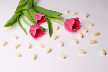 Vitamins pills on a white background and tulips
