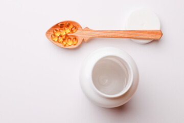 Vitamins pills in a spoon on a white background
