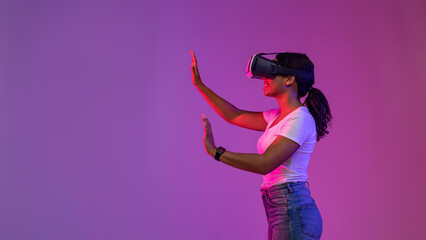 Happy black woman touching air while playing video games in vr glasses