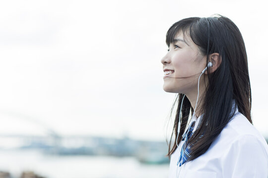 イヤホンで音楽を聴く女子学生