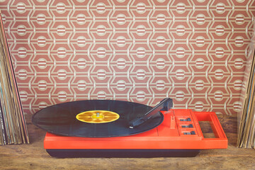 Retro styled image of a vintage record player with record albums in front of seventies wallpaper