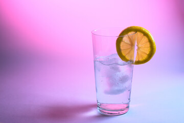 Glass of water with a slice of lemon. Creative lighting in cyberpunk style