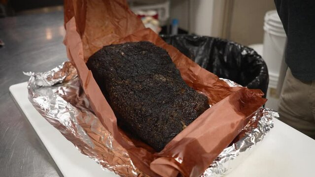 Unfolding red butcher paper to reveal Texas smoked Barbecue beef brisket, slow motion 4K