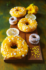 Donuts with sugar glaze and lemon on a wooden background