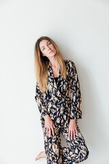 a woman in a colored suit poses against a white wall