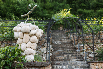 Sculpture of grapes made of stone on the background of a vineyard.