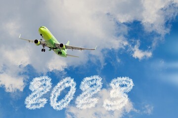 Airplane fly in blue sky with numbers 2023 in clouds