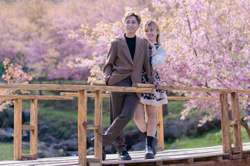 Young couple Teenage happy in the fresh beautiful Cherry pink blossom Sakura flowers full bloom in the park with a joyful vacation. Valentine's day lover of young fashion nature.