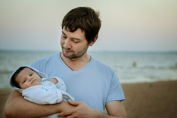 young father holding his baby son at sea side