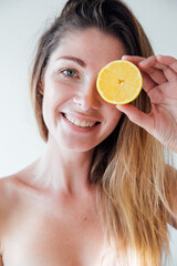 portrait of a woman with an orange by the eye smiling