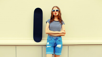 Portrait of stylish young woman with skateboard in the city © rohappy