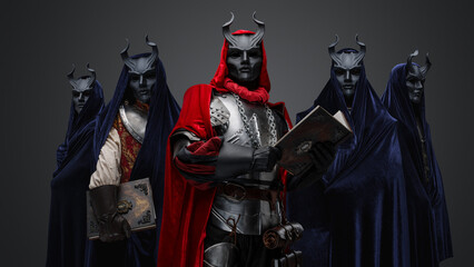 Portrait of dark cult members dressed in robes and their leader holding book.