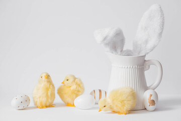 Banner. The concept of the holiday. Easter eggs, a white jug with protruding hare ears and yellow chickens on a white isolated background. Beautiful Easter card.
