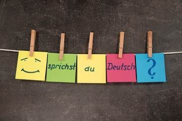 Napis w języku niemieckim Czy mówisz po niemiecku na kolorowych karteczkach zawieszonych na sznurku na ciemnym tle. Koncepcja nauki języka