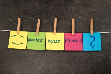 kolorowe kartki z napisem parlez vous francais na ciemnym tle. Koncepcja nauki języka