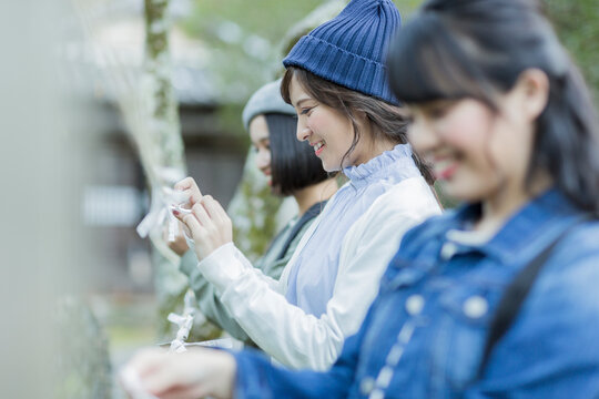 おみくじを結ぶ若い女性