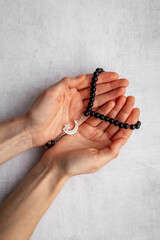 Islamic prayer concept. Hands holding Muslim rosary with silver crescent moon