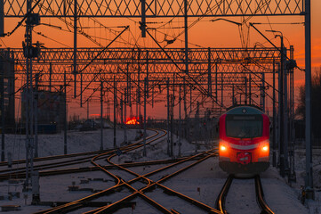 Stacja kolejowa Warszawa Główna Jadący pociąg na torach kolejowych w czasie zachodzącego słońca - obrazy, fototapety, plakaty