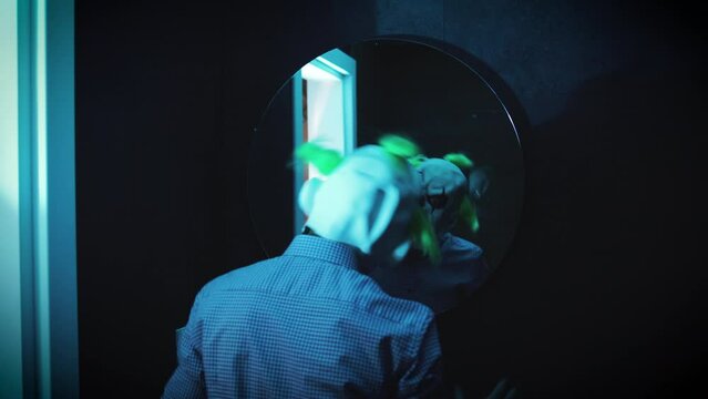 deranged killer clown looks at himself in a bathroom mirror