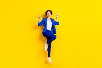 Fototapeta na wymiar Full length photo of funny pretty lady dressed blue blazer jumping high showing two v-signs isolated yellow color background