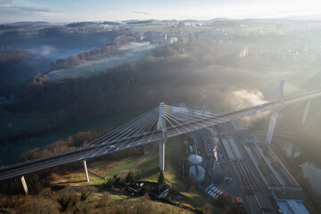 Grand pont suspendu au dessus d'une rivière, avec la brume un matin d'hiver
