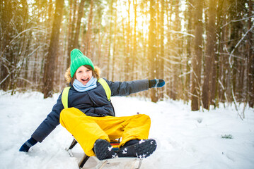 Fototapeta na wymiar happy emotional screaming smiling boy sledding in winter snowy forest
