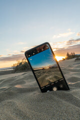Photograph seen through the cell phone stuck in the sand of the beach during the spring summer...