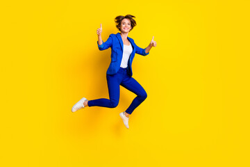 Fototapeta na wymiar Full length photo of cute sweet lady dressed blue blazer jumping high showing two thumbs up isolated yellow color background