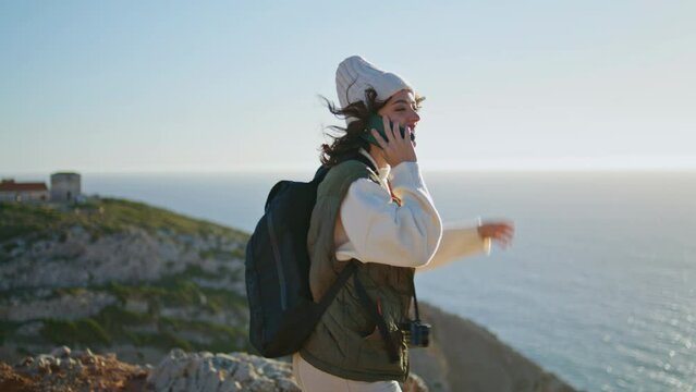 Happy tourist speaking smartphone at ocean sunset. Joyful girl enjoy landscape
