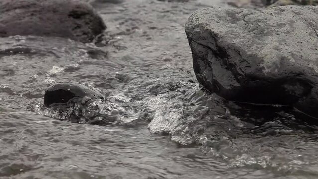 Neues Stream with fast flowing water passing large and small stones on Madeira Island
