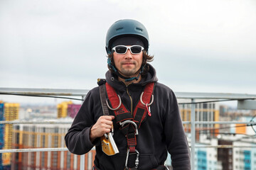 Portrait industrial mountaineering worker in uniform on roof skyscraper at buildings background....