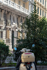 Fototapeta na wymiar Retro beige scooter in front of the classical building on the streets of Madrid on a sunny day.