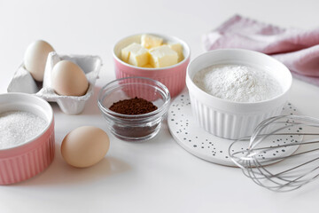 Fototapeta na wymiar ingredients for baking chocolate cake on white table with kitchen utensils. closeup