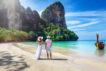 A happy couple stands on the beautiful beach of Railay, Krabi, Thailand, during their summer vacations