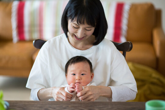 あかちゃんを膝の上に座らせている母親