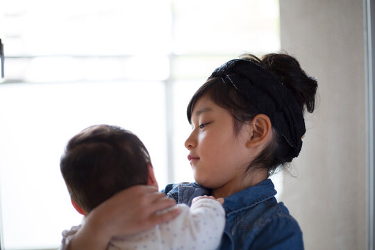 あかちゃんの弟を抱く小学生の姉
