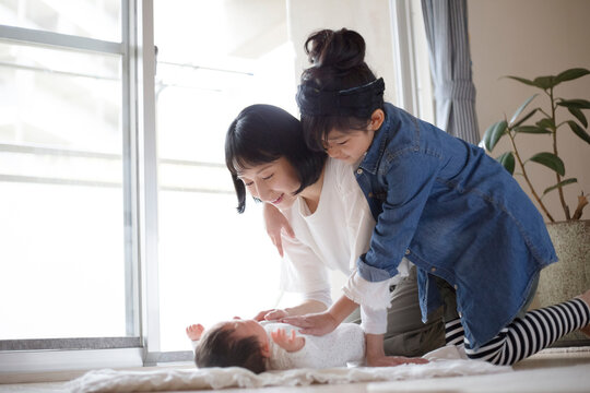 あかちゃんの世話をする母親と小学生の女の子