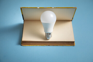 Light bulb and book on the blue background. Knowledge and wisdom
