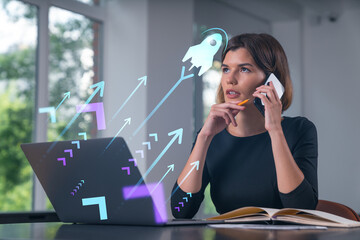 Pensive attractive beautiful businesswoman in formal wear working on laptop at office workplace in background. Concept of start up new business technology. Rocket icon hologram. Talking phone.