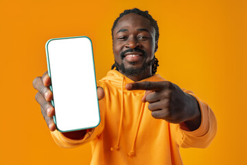 Smiling african man pointing at cellphone with blank screen with copy space