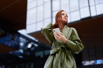 Fashion business woman with phone in hand in trendy clothes walking around town near office...