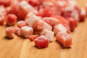 Diced Bacon on a wooden cutting board, close up.