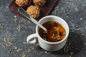 Still life - a cup of herbal tea on the table. Sweet food on a dark background
