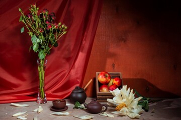 Still life of flowers - stems of a blooming rose. Draped background - theatrical stage lighting