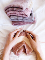hands of woman knitting woolen hat on needles