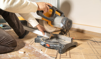Worker cutting part of furniture with cutting machine.