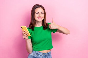 Photo of cute lovely girl hold smart phone demonstrate thumb up approval isolated on pink color background