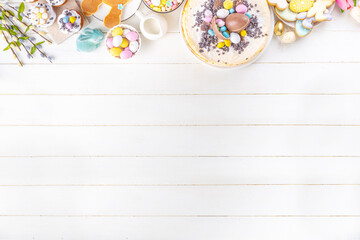 Easter brunch, breakfast food, Kids Easter party buffet. Various traditional Easter sweets, candy, pasties and baking - cross buns, cheesecake, chocolate eggs, pancakes, cupcakes, top view copy space