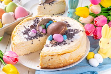 Homemade Easter cheesecake, sweet cottage cheese baking, with Easter chocolate eggs and chocolate drops, with holiday decorations and spring flowers