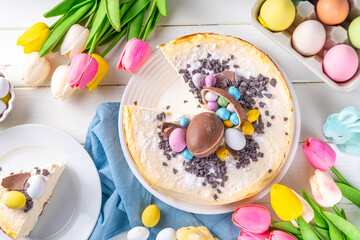 Homemade Easter cheesecake, sweet cottage cheese baking, with Easter chocolate eggs and chocolate drops, with holiday decorations and spring flowers